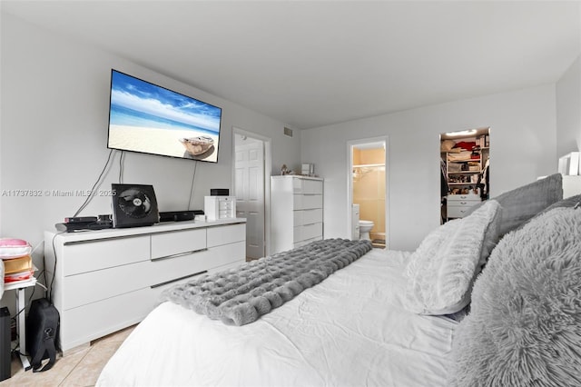 bedroom featuring light tile patterned floors, visible vents, and ensuite bathroom