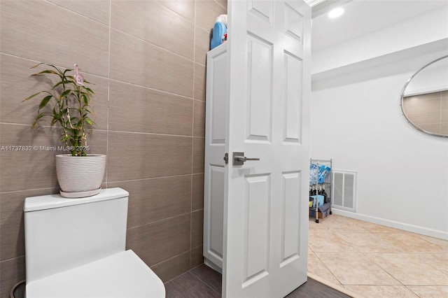 bathroom with tile patterned flooring, visible vents, tile walls, and toilet