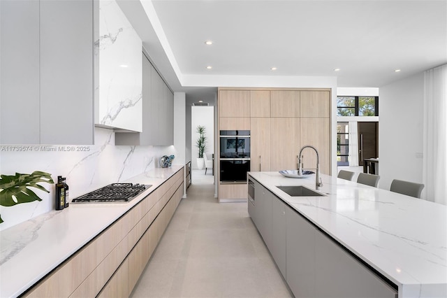 kitchen with light brown cabinetry, sink, tasteful backsplash, and a breakfast bar