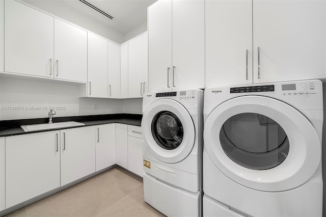 washroom with cabinets, washing machine and clothes dryer, and sink