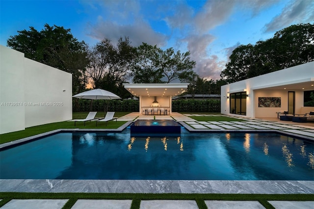 pool at dusk with a bar, an outdoor living space, and a patio