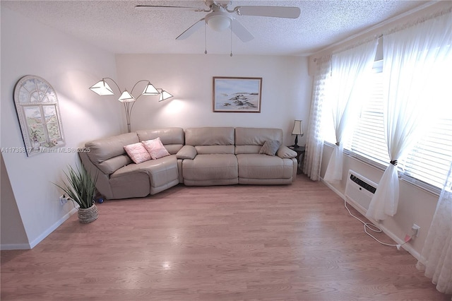 unfurnished living room featuring ceiling fan, light hardwood / wood-style floors, an AC wall unit, and a textured ceiling