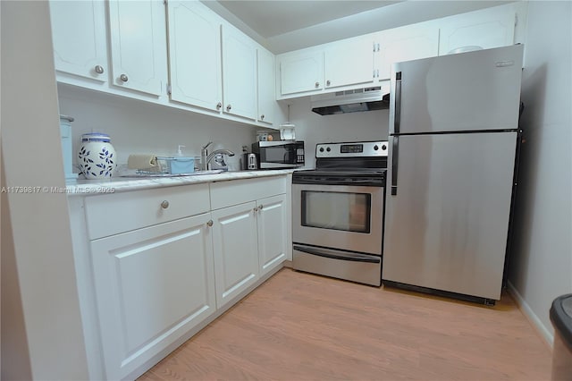 kitchen with appliances with stainless steel finishes, white cabinets, and light hardwood / wood-style floors