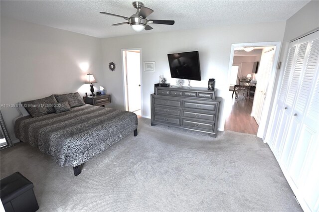 carpeted bedroom featuring ceiling fan, a closet, and a textured ceiling