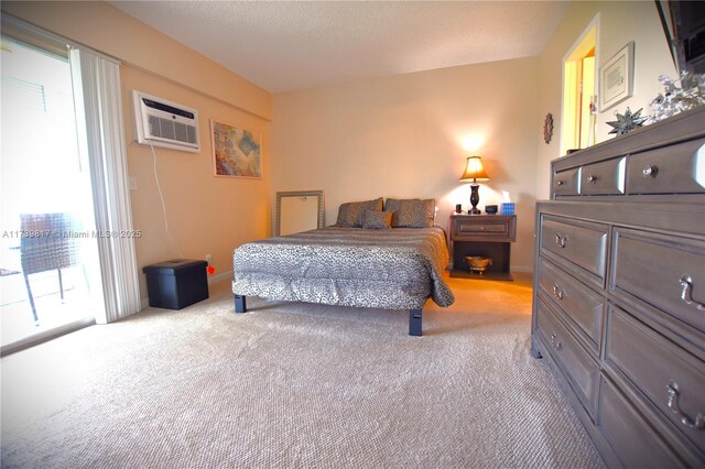 carpeted bedroom with a wall mounted AC, access to exterior, and a textured ceiling