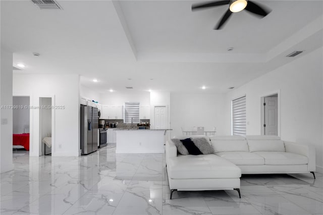 living room featuring ceiling fan and a tray ceiling