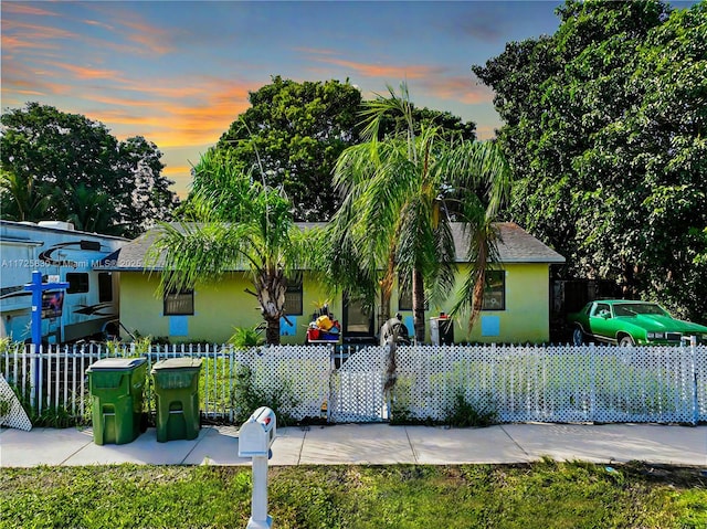 obstructed view of property with a fenced front yard and stucco siding