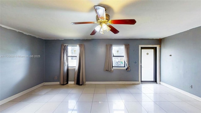 empty room featuring light tile patterned flooring, a ceiling fan, and baseboards