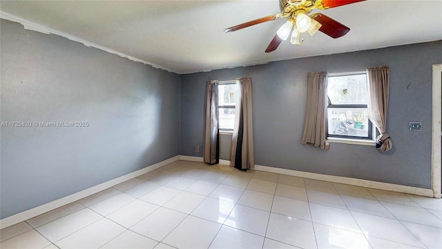 tiled spare room featuring a ceiling fan, a wealth of natural light, and baseboards