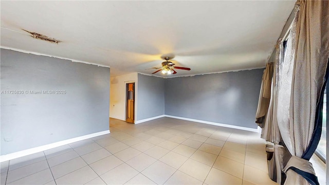 empty room with light tile patterned flooring, ceiling fan, and baseboards