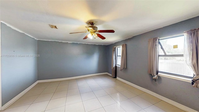 unfurnished room featuring light tile patterned floors, plenty of natural light, a ceiling fan, and baseboards