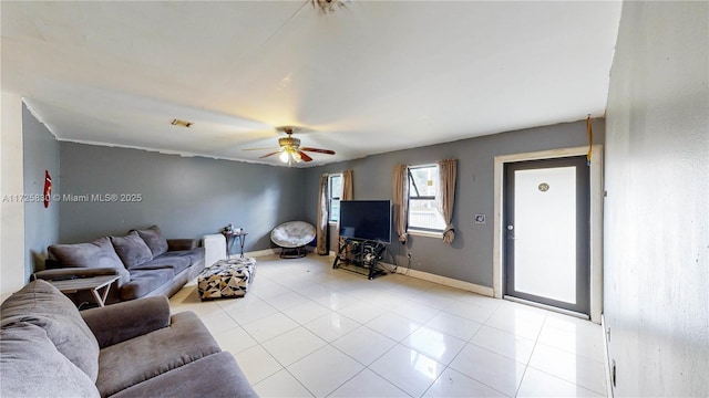 living area with light tile patterned flooring, a ceiling fan, and baseboards