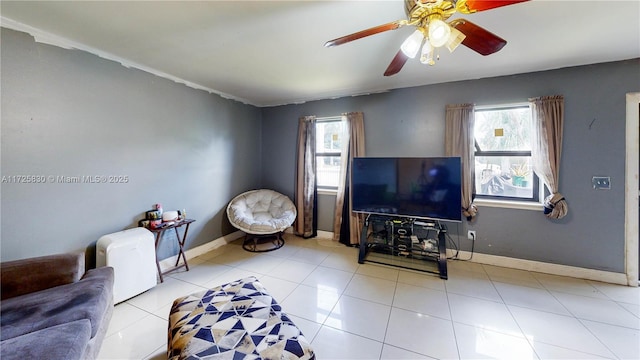 tiled living area with ceiling fan and baseboards