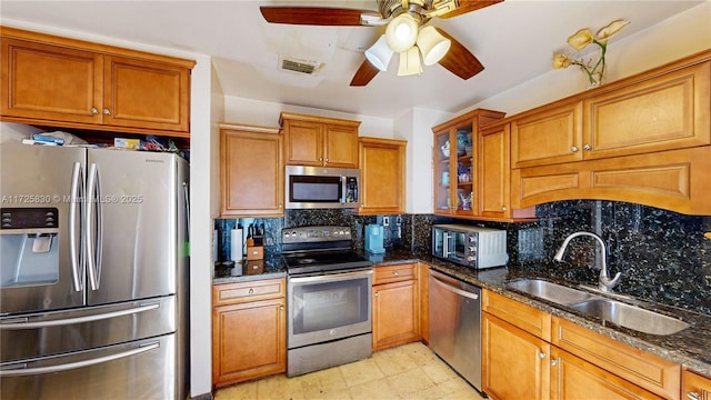 kitchen with appliances with stainless steel finishes, brown cabinetry, a sink, and tasteful backsplash