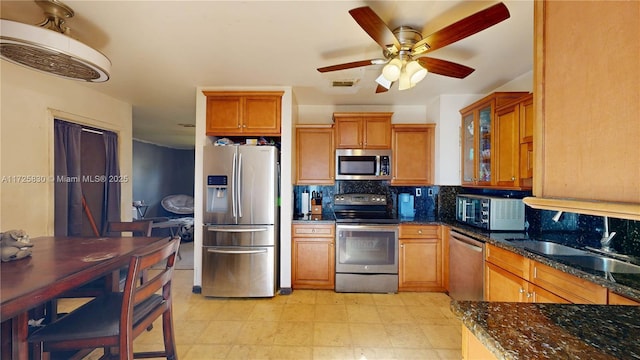 kitchen with visible vents, dark stone counters, appliances with stainless steel finishes, brown cabinets, and backsplash