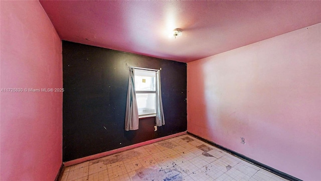 empty room with baseboards and light floors