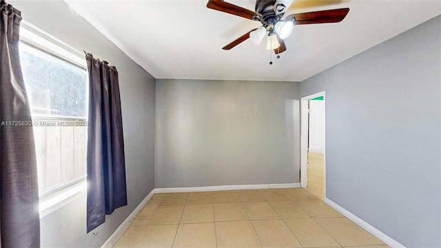 unfurnished room with a ceiling fan, tile patterned flooring, and baseboards