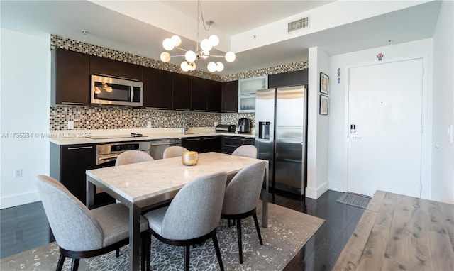 dining room featuring sink, a tray ceiling, dark wood-type flooring, and a chandelier