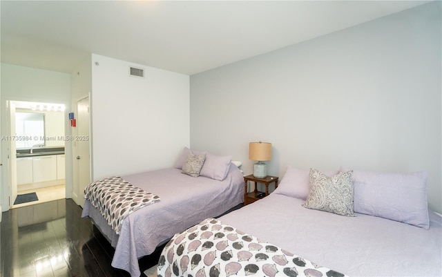 bedroom featuring connected bathroom and dark hardwood / wood-style floors