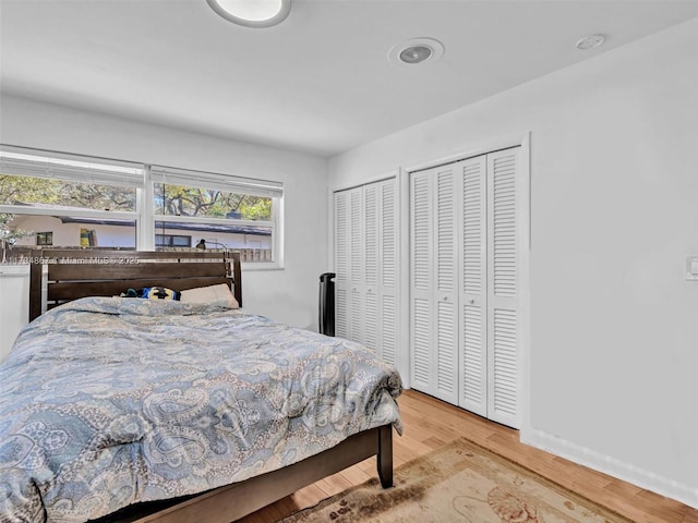 bedroom featuring multiple closets and wood finished floors