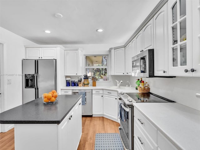 kitchen featuring appliances with stainless steel finishes, white cabinetry, glass insert cabinets, and light wood-style flooring