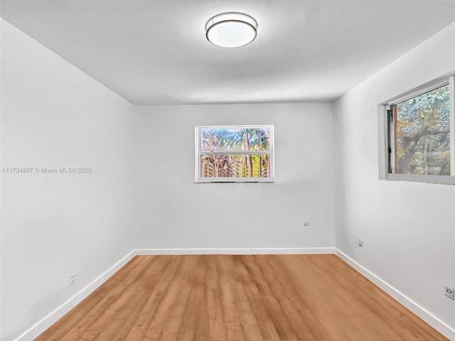 unfurnished room with light wood-style flooring, a wealth of natural light, and baseboards