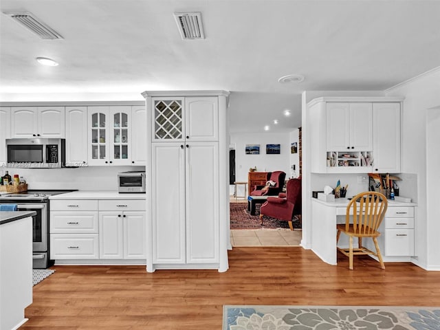 kitchen with appliances with stainless steel finishes, light wood-type flooring, and visible vents