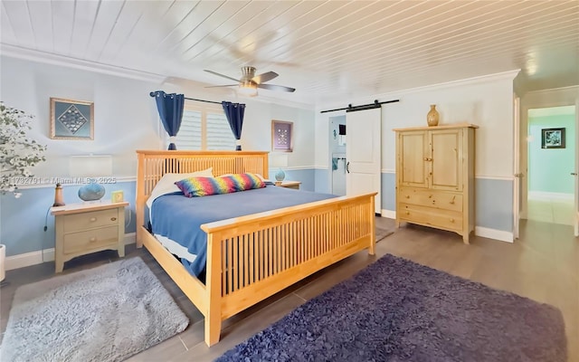 bedroom featuring wood ceiling, crown molding, ceiling fan, dark hardwood / wood-style flooring, and a barn door