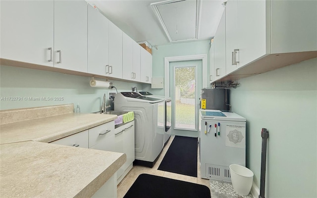 laundry room with cabinets, washing machine and dryer, sink, and water heater