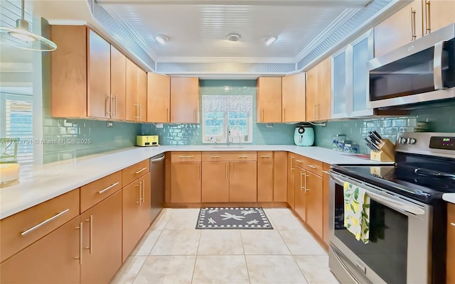 kitchen featuring sink, crown molding, light tile patterned floors, appliances with stainless steel finishes, and decorative backsplash