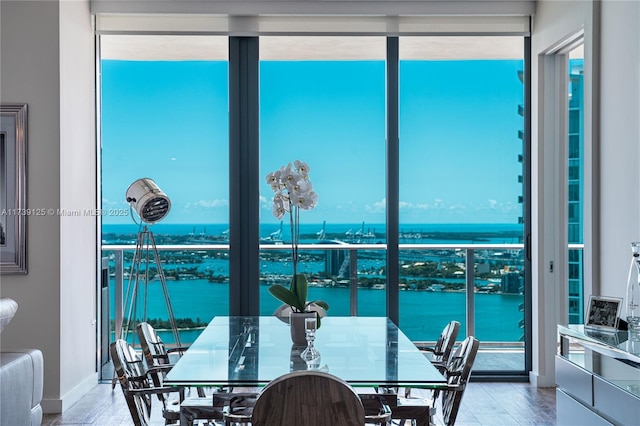 dining room featuring expansive windows, a water view, wood finished floors, and baseboards