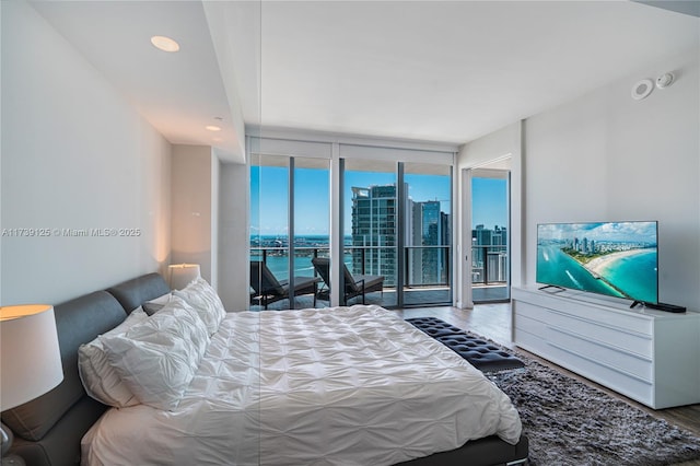 bedroom with floor to ceiling windows, recessed lighting, wood finished floors, and access to exterior