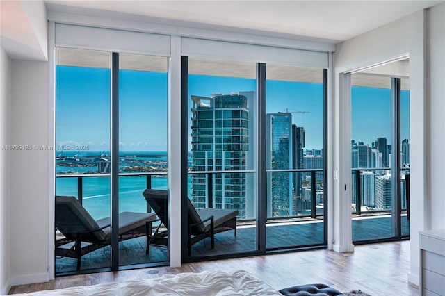 interior space with a wall of windows, a city view, a water view, and wood finished floors