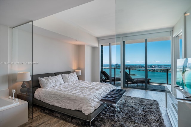 bedroom with expansive windows, access to outside, and wood finished floors