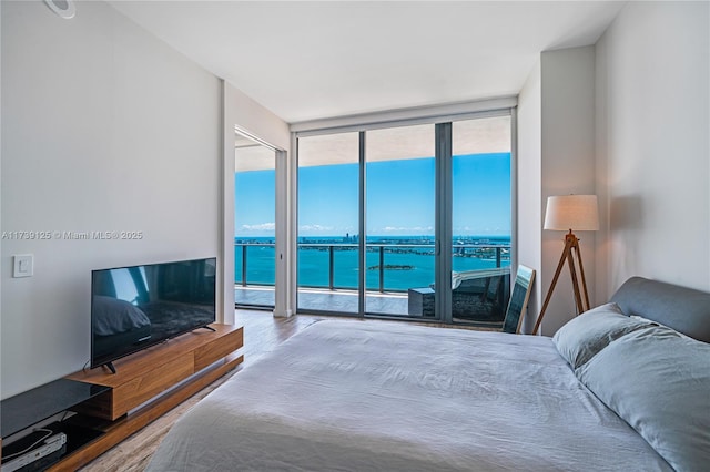 bedroom with hardwood / wood-style flooring, a wall of windows, and access to outside