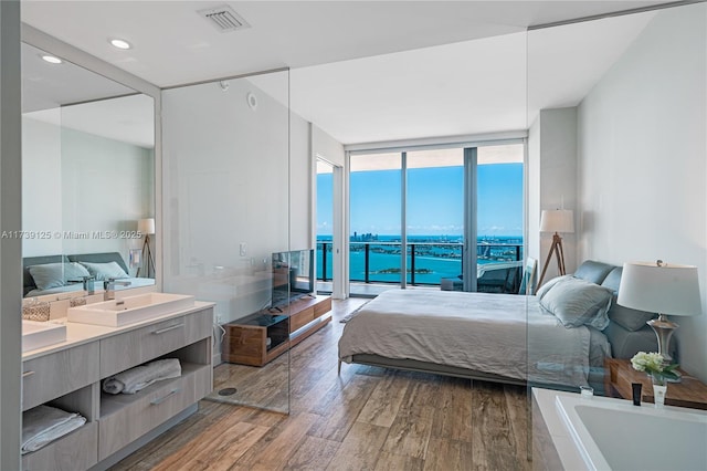 bedroom featuring floor to ceiling windows, sink, wood-type flooring, and access to outside