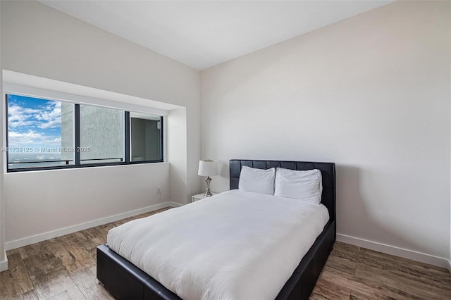 bedroom with dark wood-type flooring and baseboards