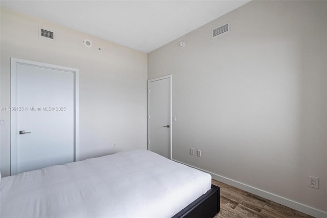 bedroom with baseboards, visible vents, and dark wood-style flooring