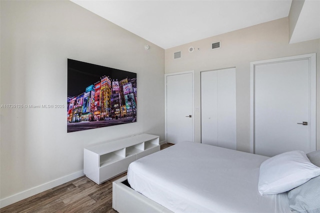 bedroom with a closet, visible vents, baseboards, and wood finished floors