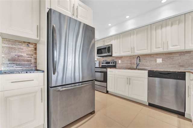 kitchen featuring light tile patterned flooring, sink, white cabinetry, tasteful backsplash, and appliances with stainless steel finishes