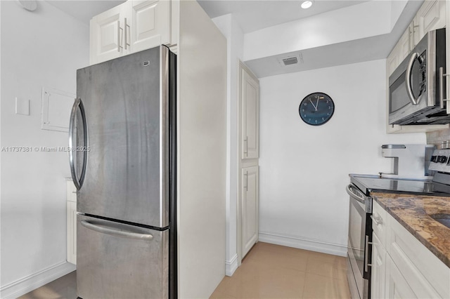 kitchen with light tile patterned floors, stainless steel appliances, and white cabinets