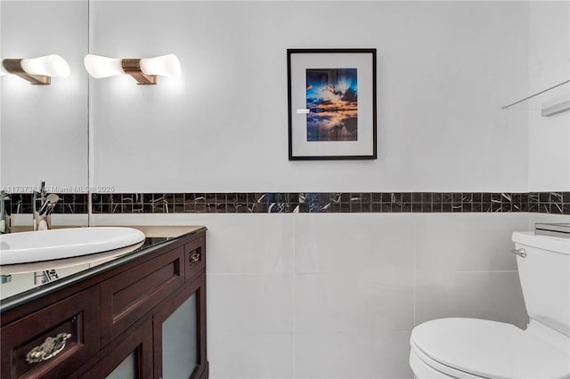 bathroom with vanity, toilet, and tile walls