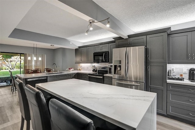 kitchen with sink, hanging light fixtures, a kitchen breakfast bar, kitchen peninsula, and black appliances