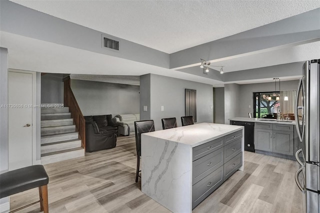 kitchen with a breakfast bar, visible vents, freestanding refrigerator, dishwasher, and gray cabinets