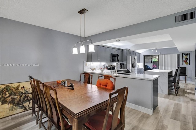 dining room featuring visible vents, light wood-style flooring, and baseboards