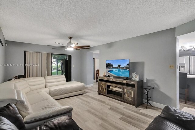 living area with wood finished floors, a ceiling fan, and baseboards