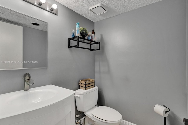 bathroom featuring toilet, a textured ceiling, visible vents, and vanity