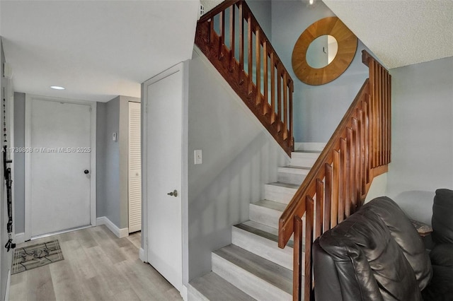 stairs with wood finished floors, recessed lighting, and baseboards