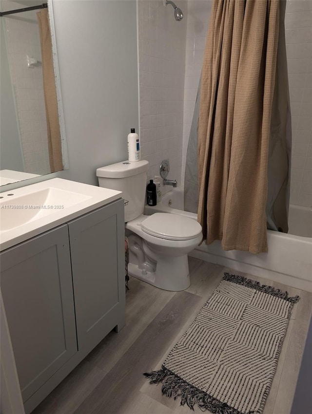 full bath with shower / tub combo, wood finished floors, toilet, and vanity
