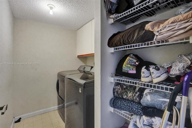 laundry room with washer and dryer, cabinet space, a textured ceiling, and baseboards